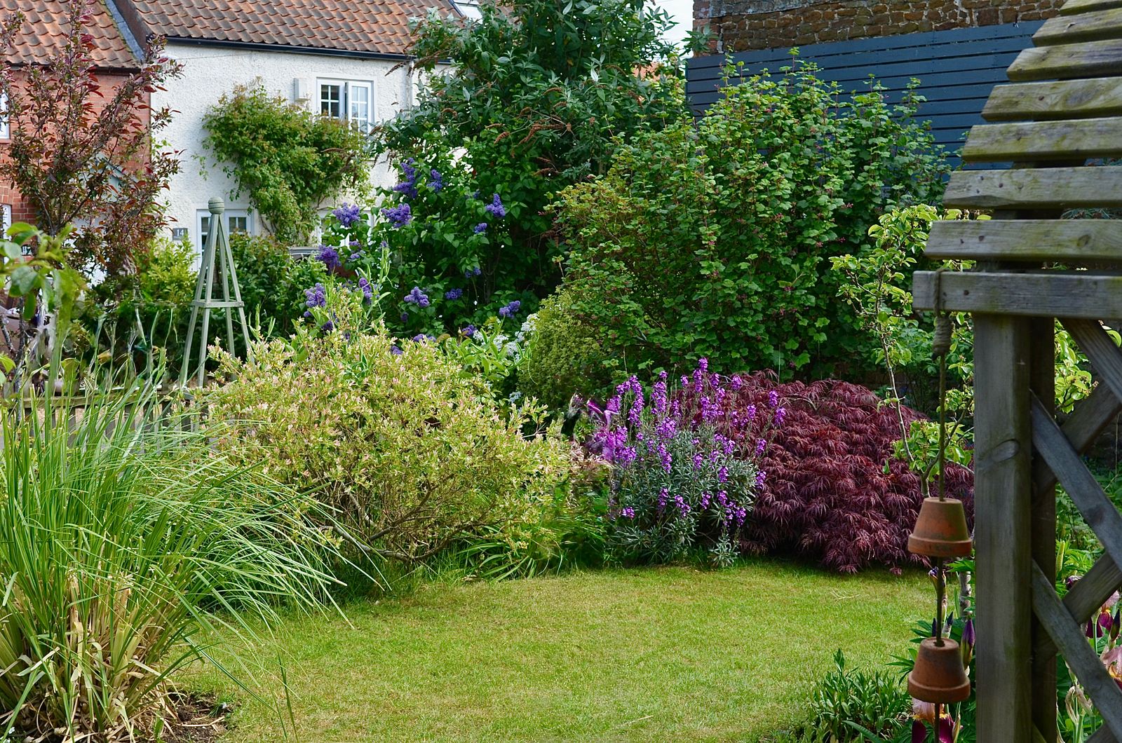 Blühender, liebevoll gestalteter Garten mit kleinem Gartenhaus